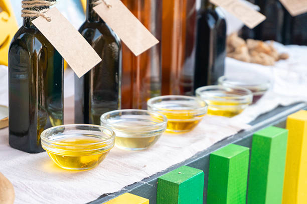 Variety of unrefined oils including olive, flaxseed, mustard, milk thistle and sesame in glass bottles and bowls on a farmers market table