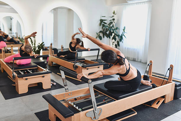istock Energetic Females Using Reformers For Pilates Stretch Workout In Bright Studio 2238335831