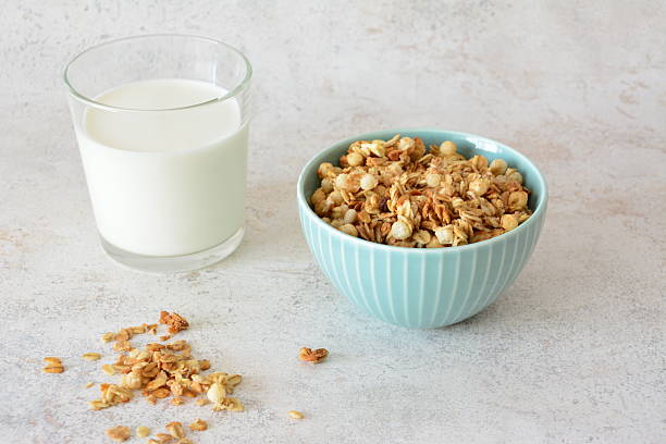 istock Granola cereal in a blue bowl with milk in a glass for breakfast on a white surface 2238340603