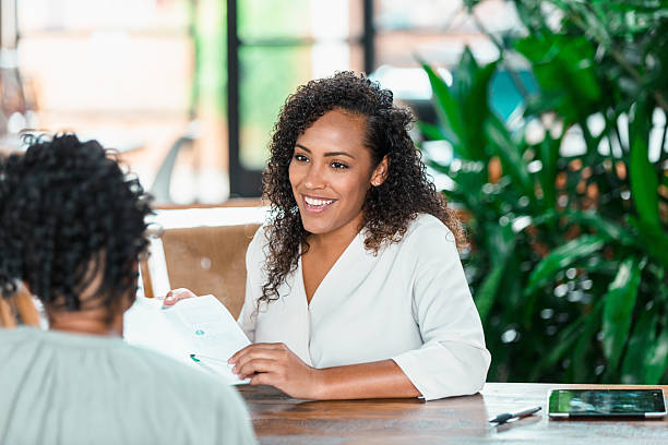 istock Two professional women engaged in a friendly discussion about documents at a table. 2238342742