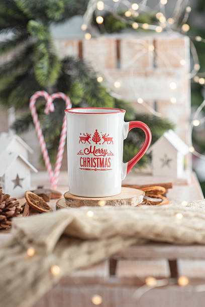 istock White ceramic mug with red handle and Christmas design, placed on wooden coaster, surrounded by festive decorations, creating a cozy holiday atmosphere with warm lights 2238344708