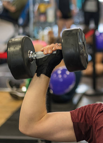 istock Person focusing on strength training and lifting a heavy dumbbell during a workout session, embodying an active lifestyle and dedication to fitness in a gym setting 2238347125