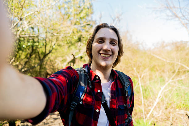 istock Young man taking a selfie in a forest - camera point of view 2238352025