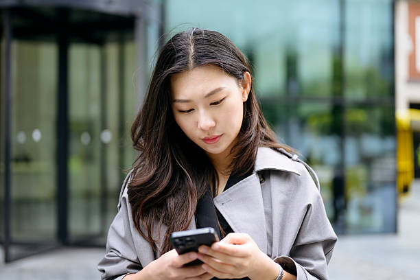 istock Young Chinese businesswoman texting on smartphone outside work 2238352141