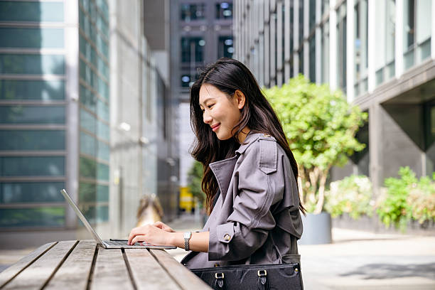 istock Young Asian businesswoman using laptop outdoors sitting at table 2238352166
