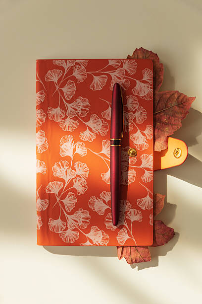 istock Autumn Notebook with Leaves and Pen on Light Background under Sun light 2238352318