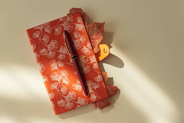 Autumn Notebook with Leaves and Pen on Light Background under Sun light