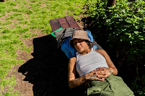 A teenage boy napping on grass, on a spring day with a bush hat covering his face
