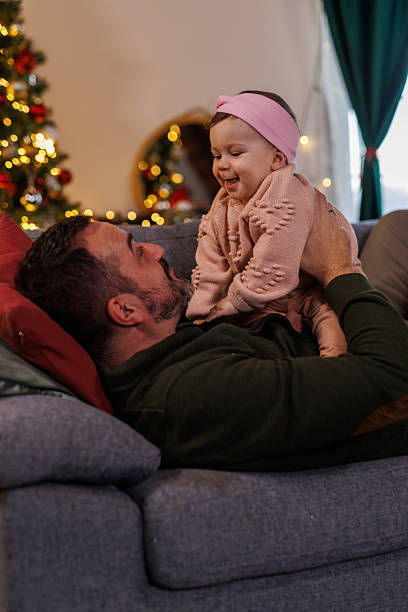 istock Man lying on the sofa, playing and cuddling with his baby daughter 2238353673