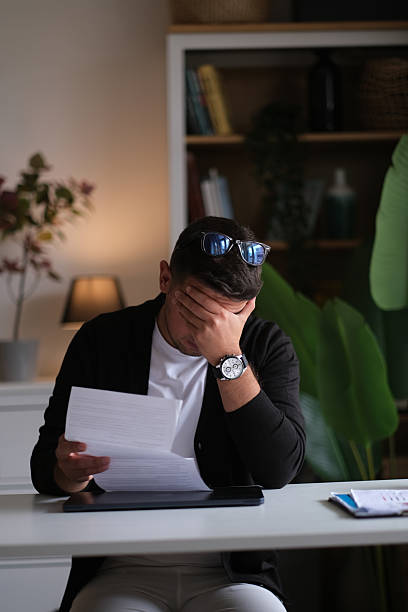 Sad man looking at financial documents at home