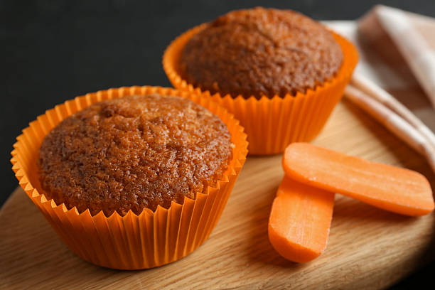 Tasty carrot muffins with fresh vegetable on black table, closeup