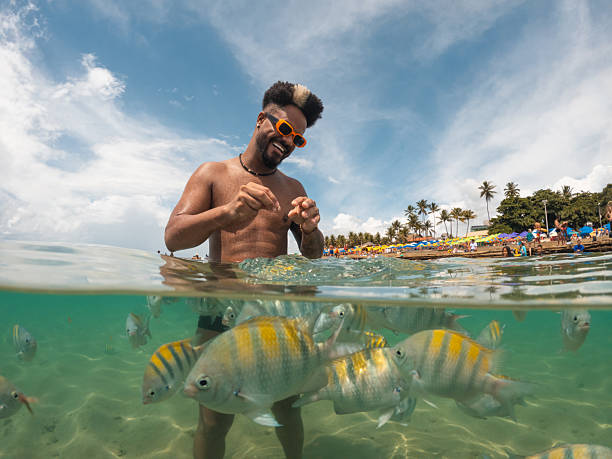 istock Afro man feeding fish on Porto de Galinhas beach 2238372074