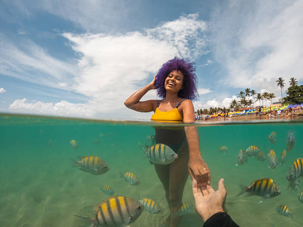 istock Afro tourist bathing with fish on a tropical beach 2238372086