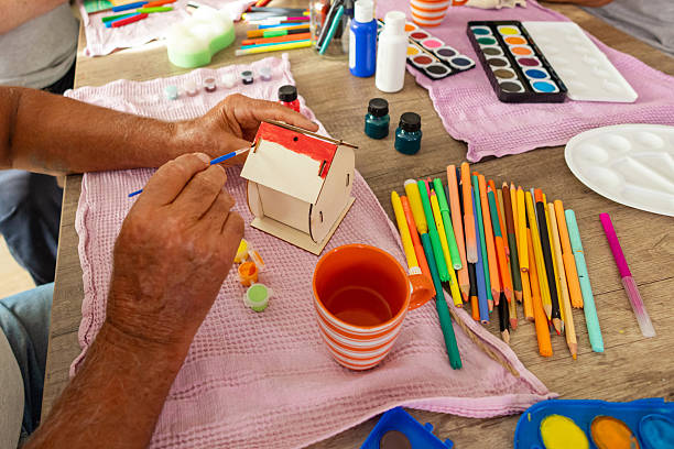 Senior resident meticulously coloring a small birdhouse, finding joy and focus through art therapy in the nursing home.