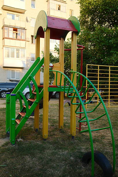istock Multi-colored playground with a slide and climbing structure stands on a grassy lawn 2238373689
