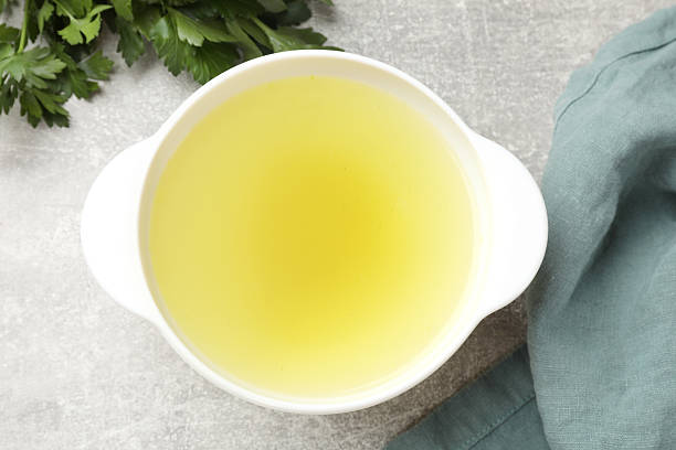 istock Tasty chicken bouillon in bowl and parsley on grey table, top view 2238376078