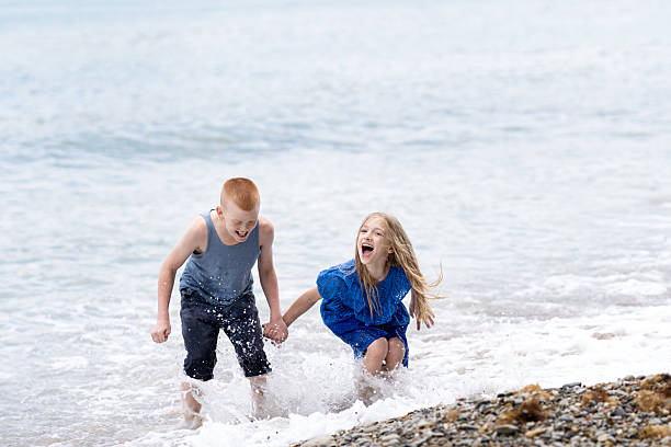istock boy and girl playing with waves 2238377798
