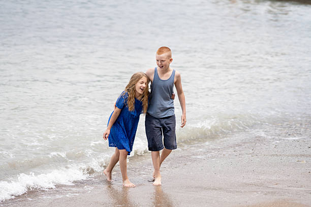 istock boy and girl playing with waves 2238377843