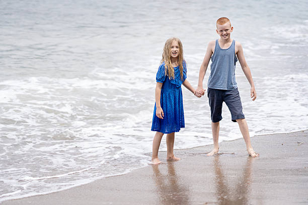 Children playing with the waves on the sea or ocean coast during a family vacation. Peaceful tropical summer holiday, travel, relaxation, summer vacation,