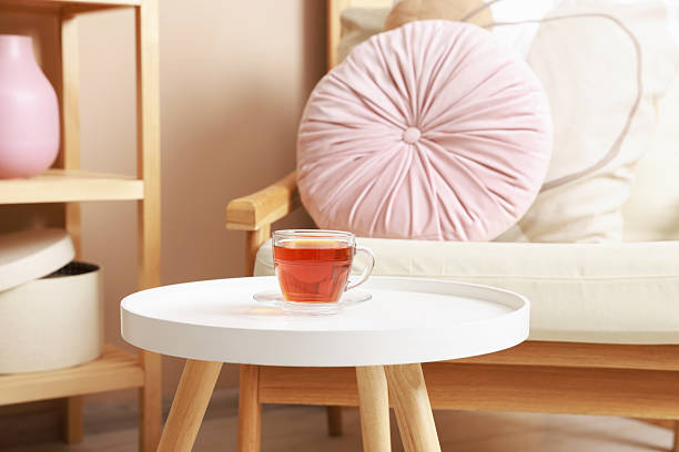 Coffee table with tea near armchair at home
