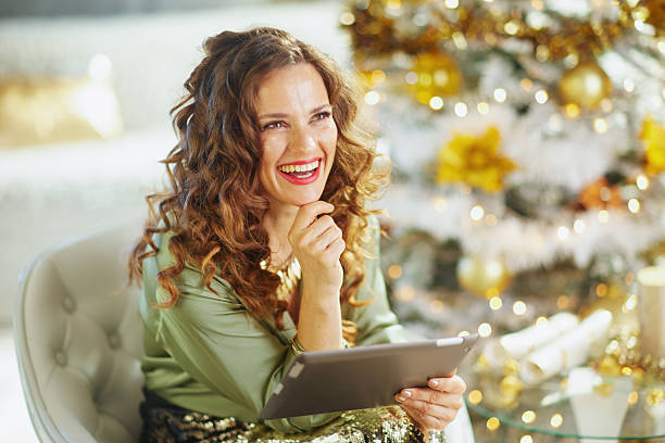 Joyful Woman with Tablet by a White Christmas Tree