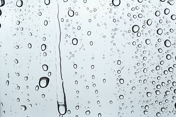 Many water drops on light glass surface, closeup
