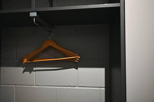 Wooden hangers hanging on a rail inside an empty gray closet with shadows