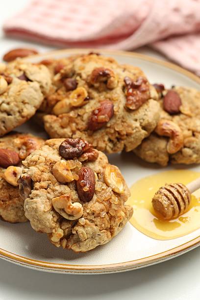 istock Tasty cookies with nuts and honey dipper on light table, closeup 2238384683