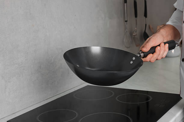 istock Chef with frying pan over cooktop in kitchen, closeup 2238386146