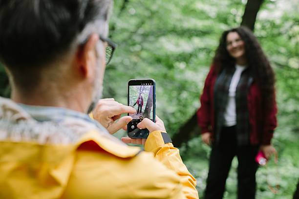 istock Father photographing daughter using smartphone in forest 2238390628