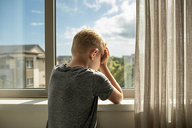 istock Sad little boy next window at home feeling lonely depressed. 2238390678