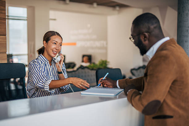 istock Receptionist assisting client and talking on telephone at desk 2238394361