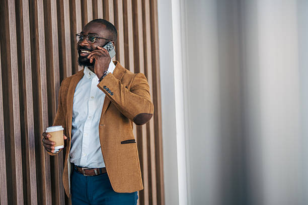 istock Smiling black businessman talking on phone, holding coffee 2238394403