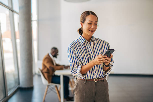 istock Businesswoman texting on phone in modern open plan office 2238394516
