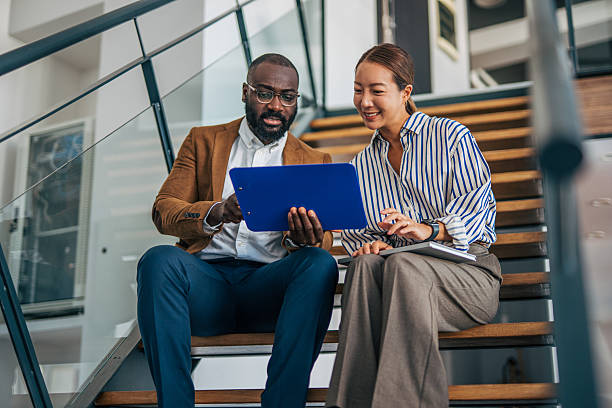 istock Diverse business people discussing documents while sitting on stairs 2238395352