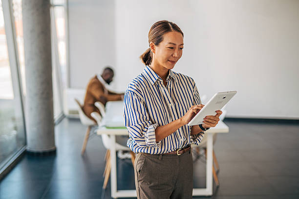 istock Asian woman standing using tablet in modern office 2238396962