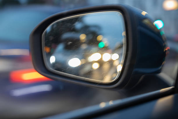 istock Blurry nighttime street reflection in a car side mirror showing approaching traffic headlights and a pedestrian, emphasizing urban travel and safety 2238399091