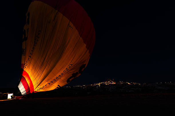 A tight shot of the Air balloon with the cauldron of Olympic flame by night, with a street light and the fences of a public park. Paris, France - July 28, 2024.