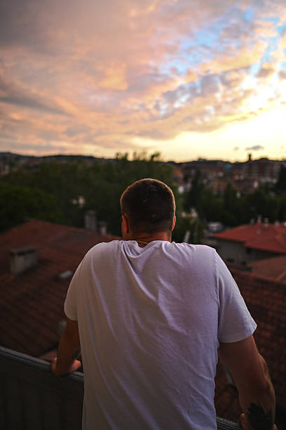 Man in white t-shirt enjoying a panoramic cityscape view during a peaceful sunset