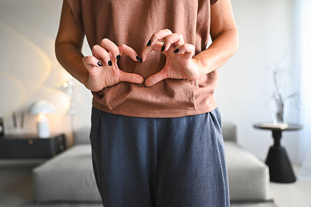 Woman forming heart shape with hands over abdomen