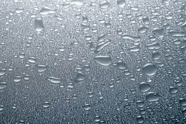 Water drops on grey glass surface, closeup