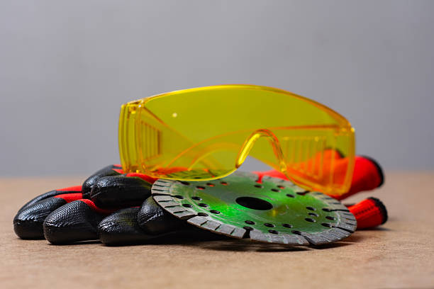 Close up portrait of manual worker in protective gear (helmet, gloves, reflective clothing) wearing goggles.