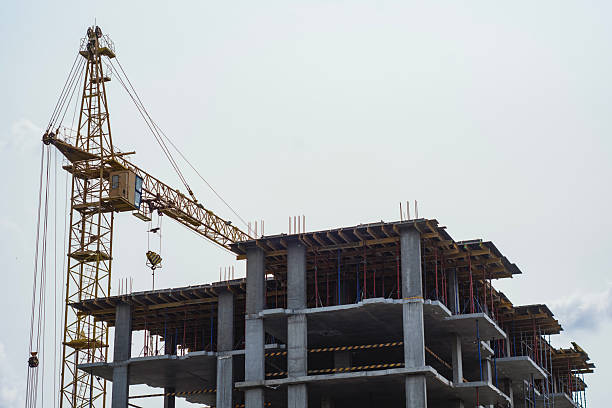 Construction site with a large tower crane at a modern building project. The unfinished building home for themes of architecture, urban development, and real estate growth.