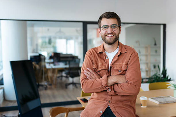 istock Smiling young businessman with eyeglasses posing in modern office 2238414075