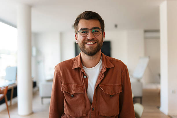 istock Young man smiling, wearing glasses and earbuds indoors 2238417732