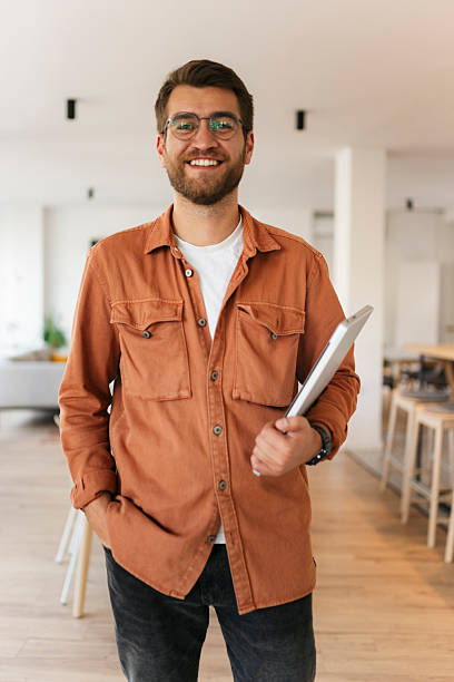 istock Smiling young man holding laptop in modern workplace 2238418671