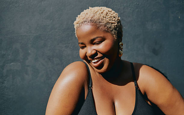 istock Joyful young Black curvy woman smiling outdoors with natural light against dark background 2238423837