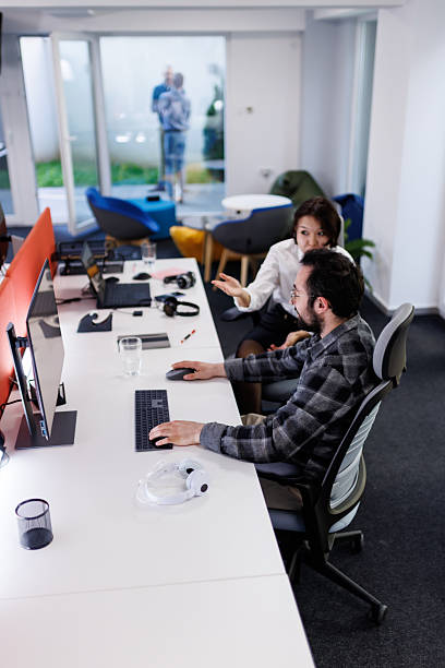 istock Business team collaborates in modern office space, discussing work and sharing ideas in a creative environment with technology on desks 2238424262