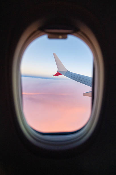 istock Plane wing among pink clouds at sunset 2238424398