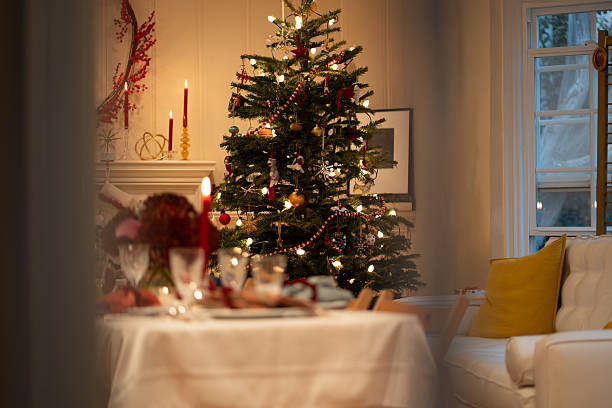 A defocused table setting in front of a lit Christmas tree on Christmas Eve.